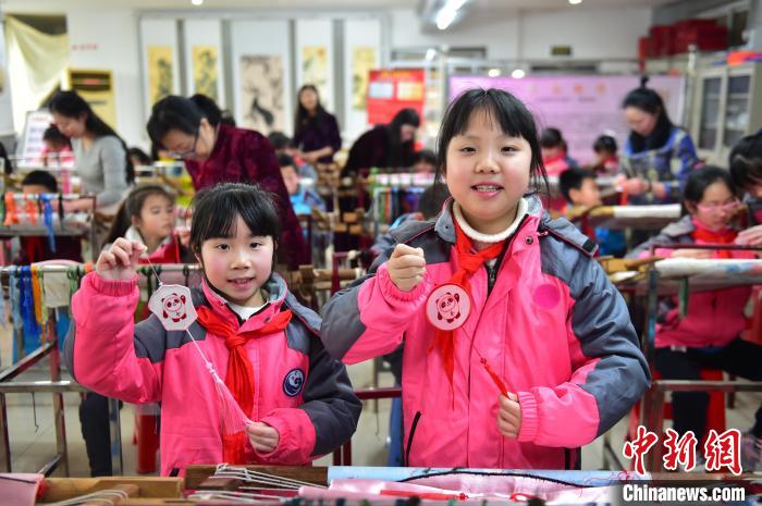 圖為小學生展示繡制好的2022年北京冬奧會吉祥物“冰墩墩”形象?！∮髟屏?攝