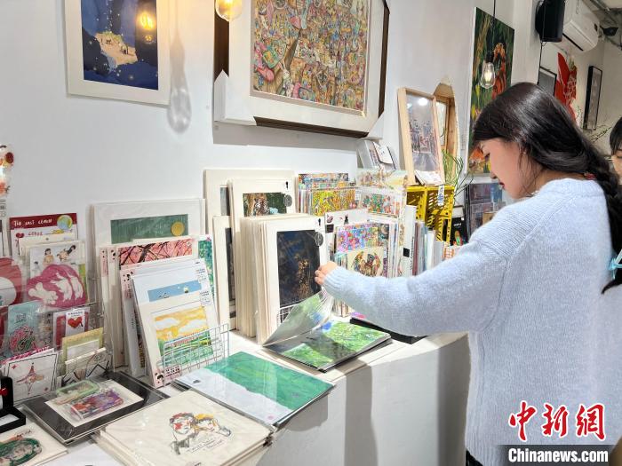 圖為藝術(shù)品商店內(nèi)，顧客挑選插畫作品?！＄婌?攝