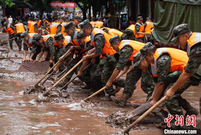 7月4日，萬(wàn)州區(qū)五橋街道，武警官兵清理街道上的淤泥。　冉孟軍 攝