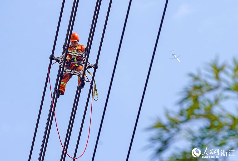 3月11日，在浙江省諸暨市河上鎮(zhèn)，浙江省送變電工程有限公司檢修人員在高空的導(dǎo)線上進(jìn)行線路檢修維護(hù)。人民網(wǎng) 章勇濤攝