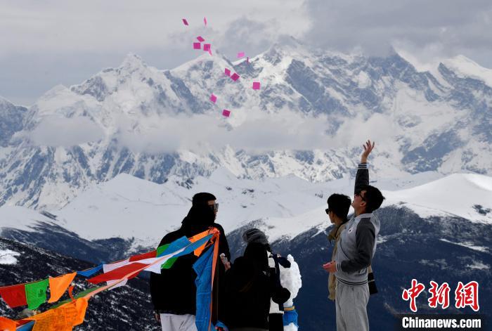 圖為5月14日，游客在西藏林芝色季拉山觀景臺拋灑“隆達”(風(fēng)馬旗，藏族民眾的一種祈福方式)。　李林 攝